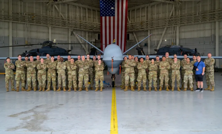174th Attack Wing personnel with MQ-9 Reaper and American flag in hangar.