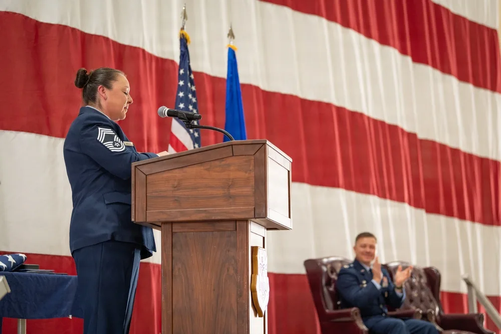 Air Force leader speaks at retirement ceremony, American flag backdrop.