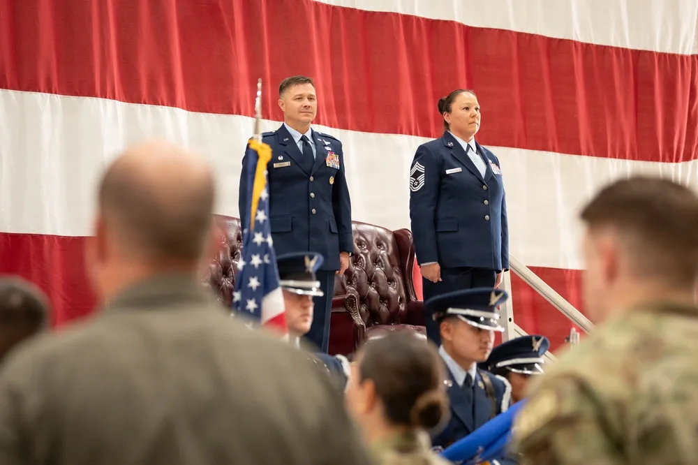 Air Force officers stand at retirement ceremony before US flag backdrop.