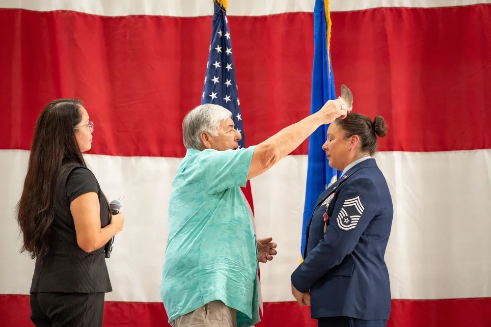 Air Force retirement ceremony with feather blessing in front of US flag.
