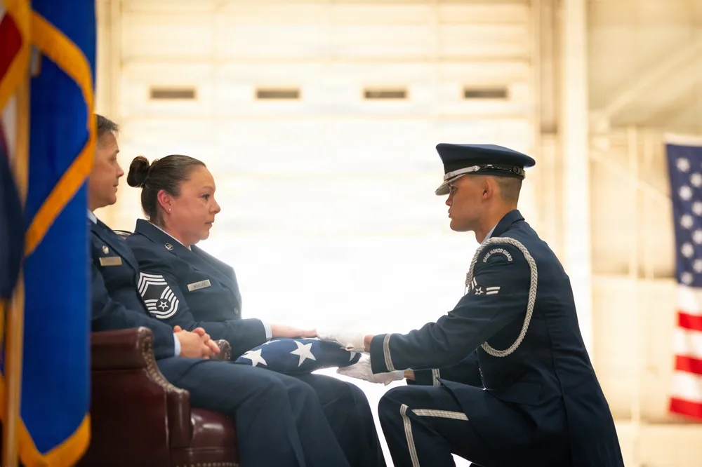 Airman presents folded flag to two women at Air Force retirement ceremony.