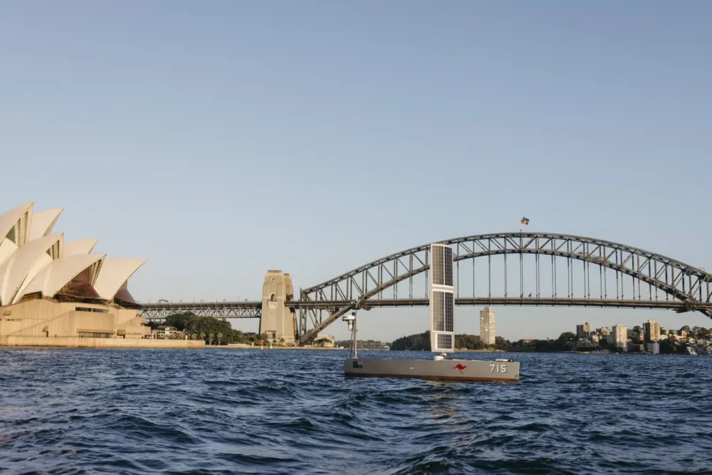 Autonomous boat sailing in Sydney Harbour with Opera House and Harbour Bridge.