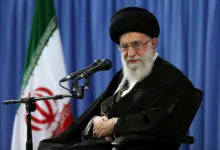 Ayatollah Ali Khamenei, Supreme Leader of Iran, seated with flag backdrop.