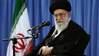 Ayatollah Ali Khamenei, Supreme Leader of Iran, seated with flag backdrop.