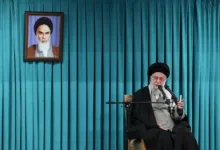 Ayatollah Ali Khamenei speaks with portrait of Ruhollah Khomeini behind him.