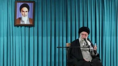 Ayatollah Ali Khamenei speaks with portrait of Ruhollah Khomeini behind him.