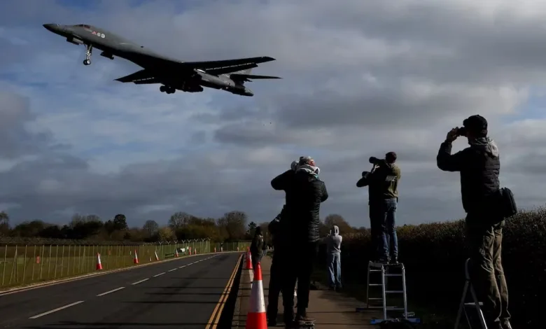 B-1B bomber plane landing, aviation enthusiasts taking photos.