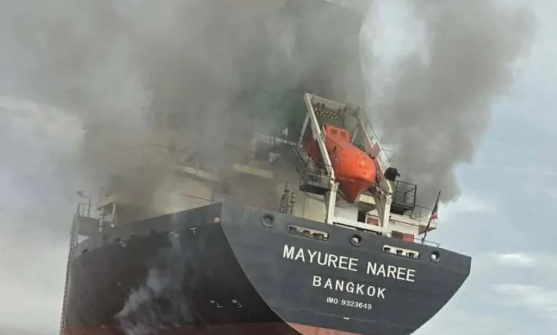 Burning cargo ship Mayuree Naree Bangkok with life rafts visible.