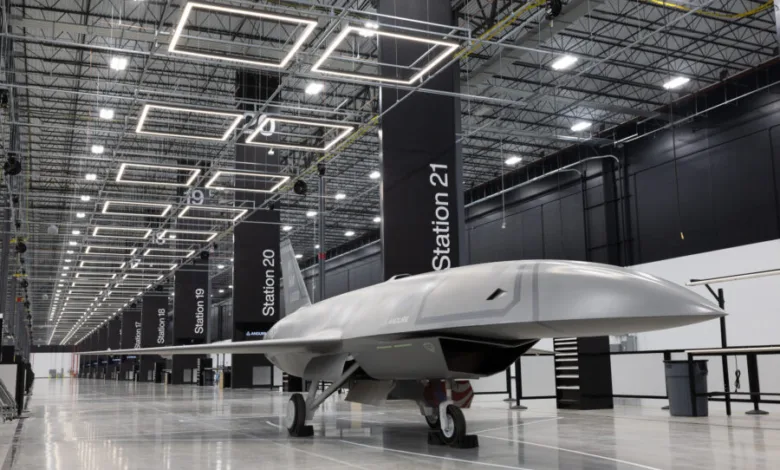 Grey drone aircraft in a modern manufacturing facility with station markers.