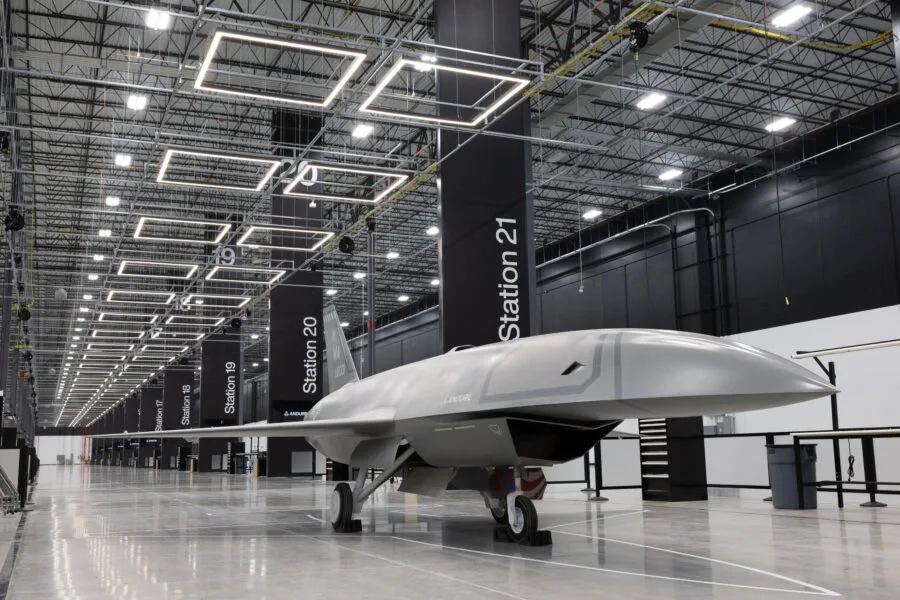 Grey drone aircraft in a modern manufacturing facility with station markers.