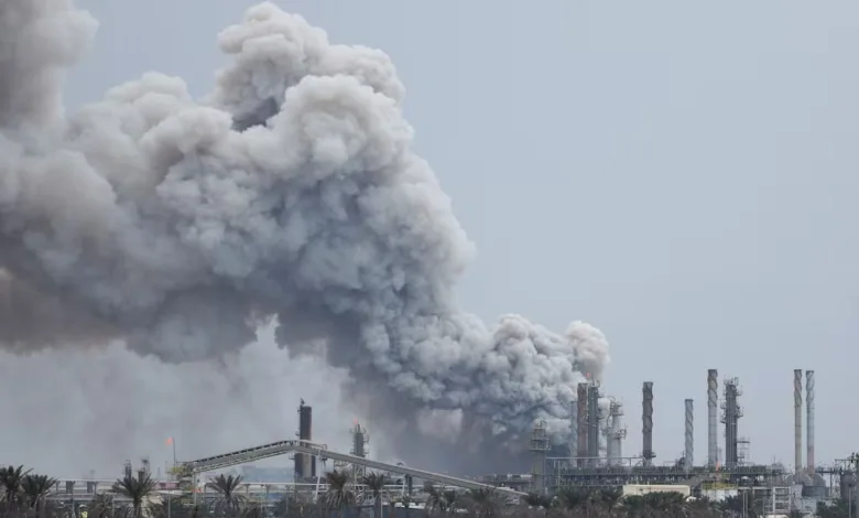 Industrial plant with large plume of smoke rising, environmental disaster.