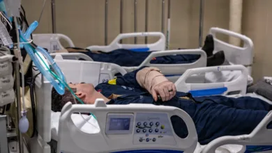 Injured sailor in hospital bed, USS Iwo Jima training support. Bandaged arm, medical equipment.