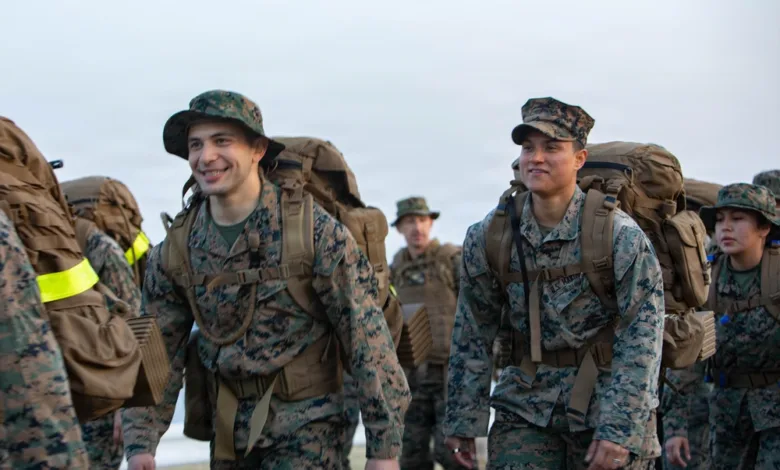 Marines hike with packs at MCAS Iwakuni, wearing camouflage uniforms and hats.
