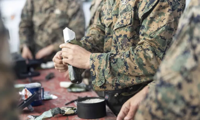 Marines preparing meals ready-to-eat (MRE) in camouflage uniforms.