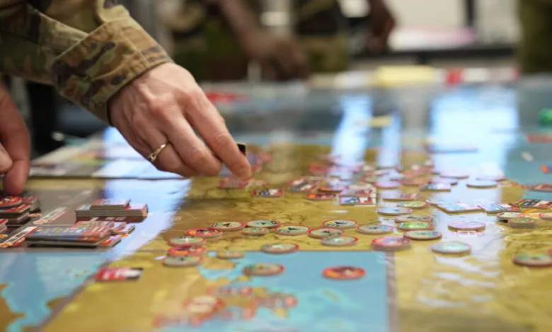 Wargame in progress, military personnel strategizing with game pieces on a map.