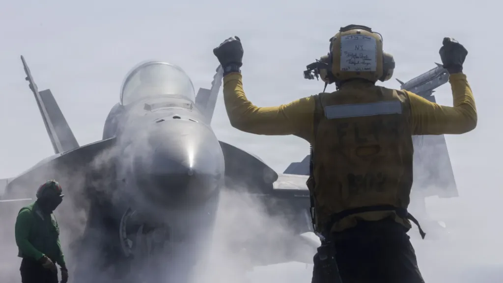 Navy aircraft director signals F-18 Super Hornet launch from aircraft carrier. Flight deck operations.