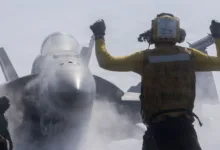 Navy aircraft director signals F-18 Super Hornet launch from aircraft carrier. Flight deck operations.