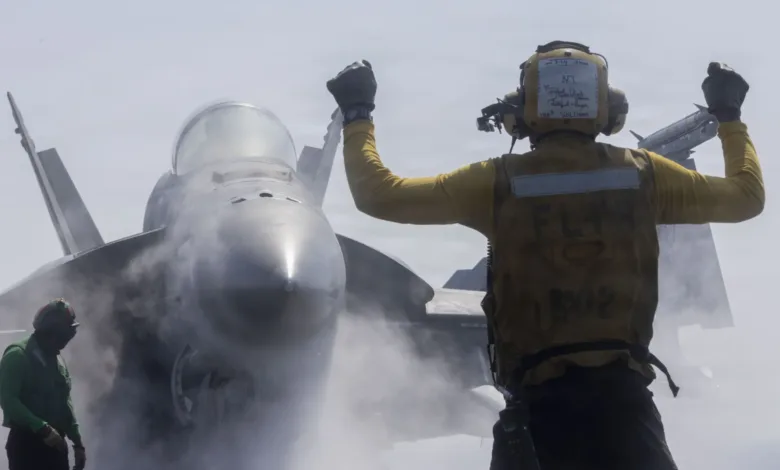 Navy aircraft director signals F-18 Super Hornet launch from aircraft carrier. Flight deck operations.