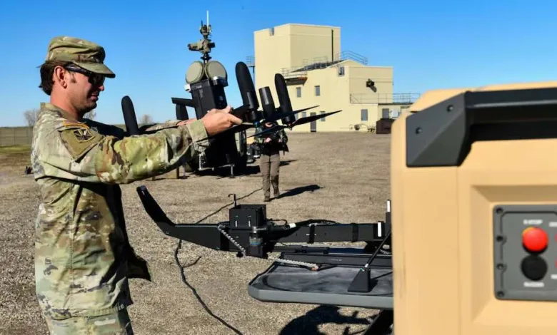 Soldier preparing a small military drone for launch in an outdoor field setting.