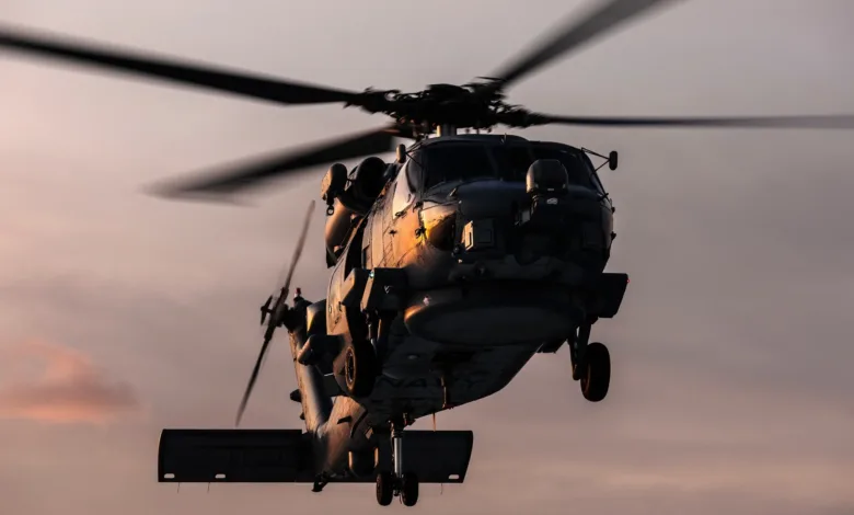 US Navy MH-60 Seahawk helicopter in flight against a dusk sky. Rotor blades blurred with motion.