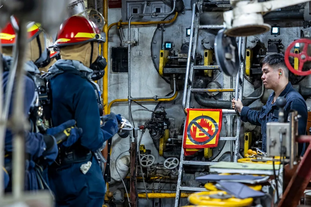 Sailors conduct fire fighting training aboard USS Iwo Jima, with a 'B' fire symbol visible.