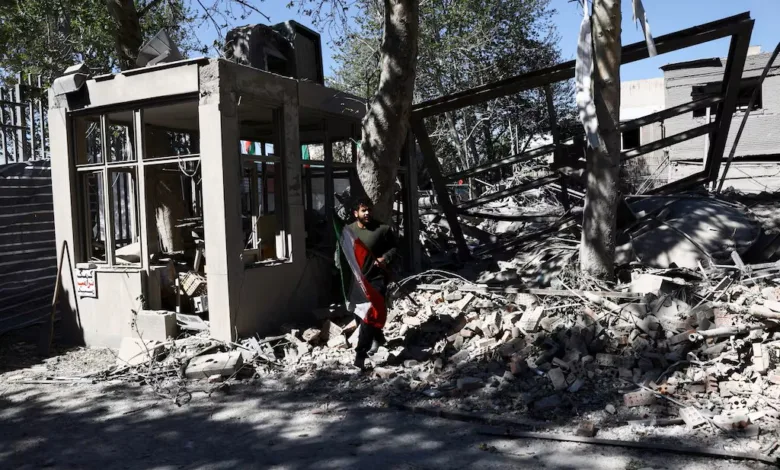Man with flag amidst building rubble, possibly Afghanistan after conflict.