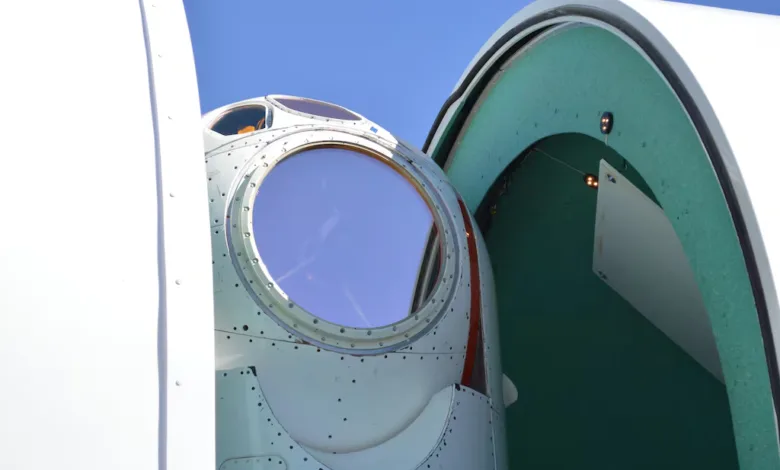 Close-up of a circular aircraft cockpit window with a blue sky reflection.