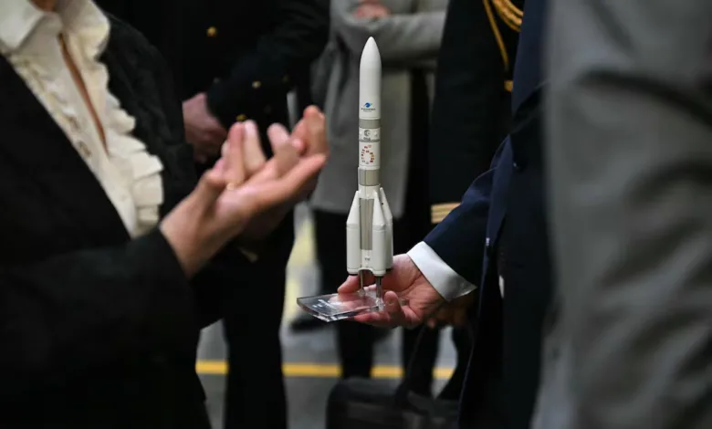 Model rocket held by man in suit, with people in background