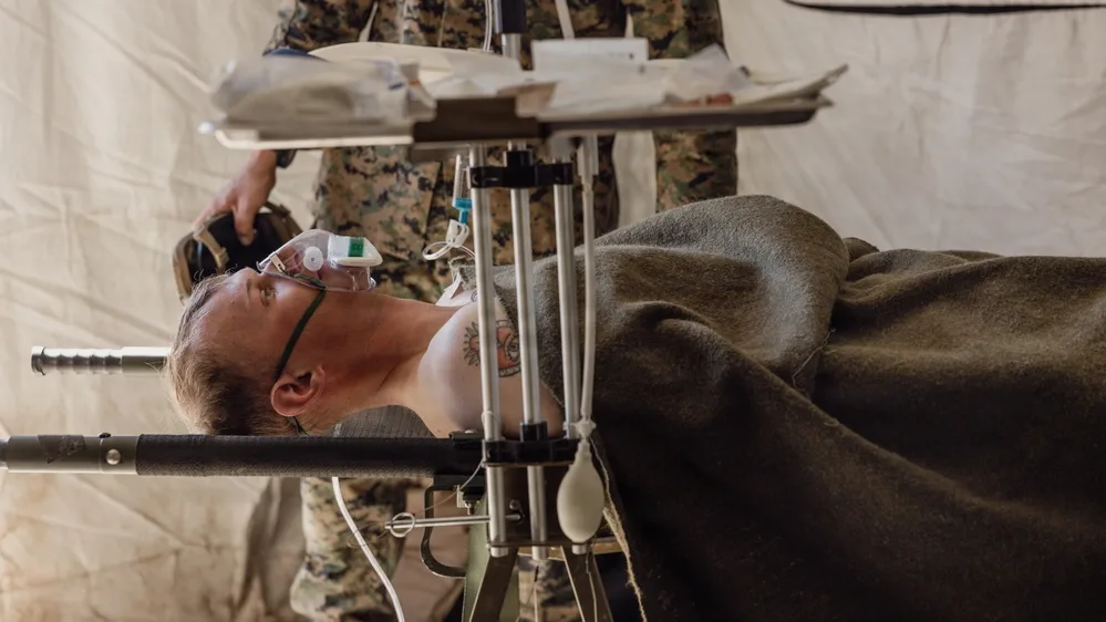 Casualty with oxygen mask on stretcher during medical training exercise.