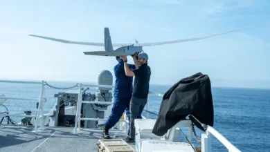 Two men preparing a drone for launch on a ship at sea.