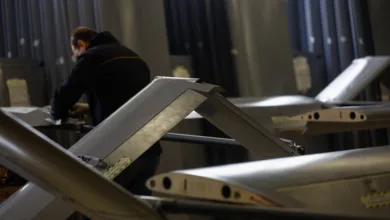 Drone wings being assembled in a factory with a worker in the background.