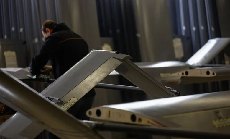Drone wings being assembled in a factory with a worker in the background.