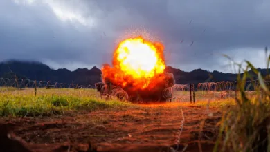 Explosion in field with barbed wire under cloudy sky.