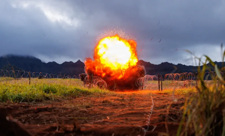 Explosion in field with barbed wire under cloudy sky.