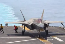F-35 fighter jet on aircraft carrier deck with crew