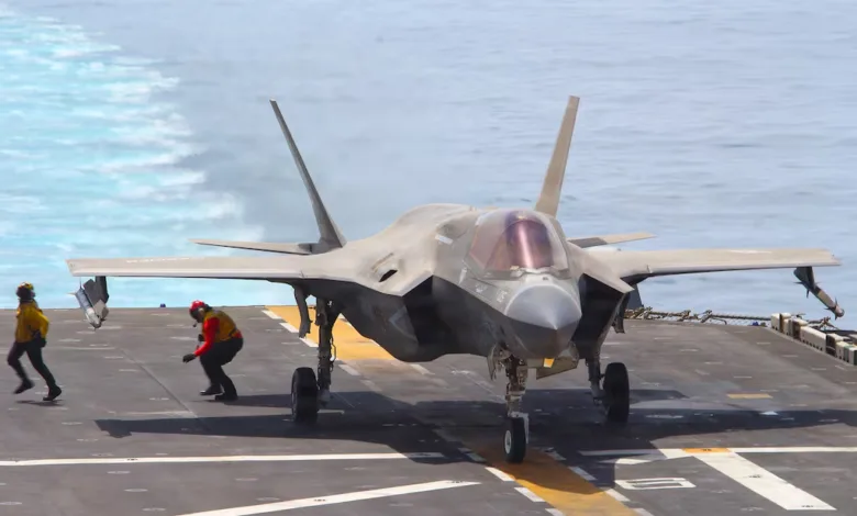 F-35 fighter jet on aircraft carrier deck with crew