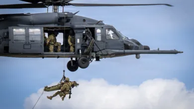Helicopter hoists medic and patient on a stretcher during training exercise.