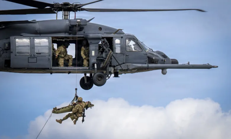 Helicopter hoists medic and patient on a stretcher during training exercise.