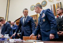 Military and civilian leaders confer in a government hearing room.