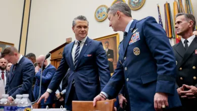 Military and civilian leaders confer in a government hearing room.