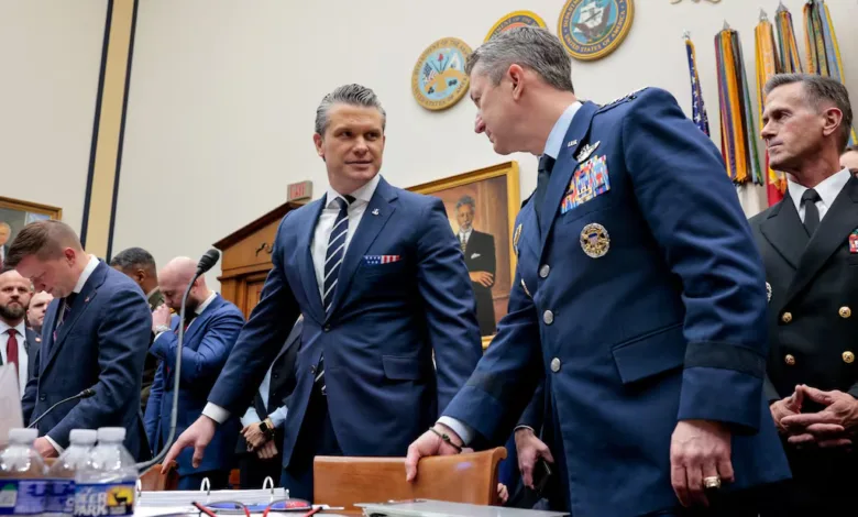 Military and civilian leaders confer in a government hearing room.