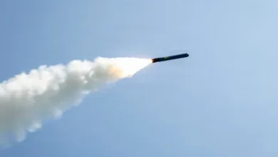 Missile launch with smoke trail against a clear blue sky, ascending rapidly.