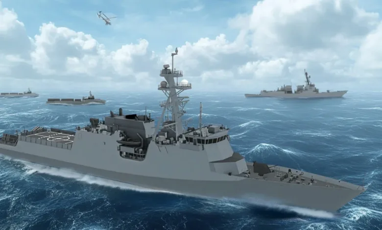 Modern naval frigates and cargo ships sail in formation on the ocean under a cloudy sky.