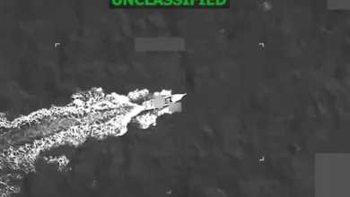 Unclassified aerial view of a naval vessel leaving a white wake.