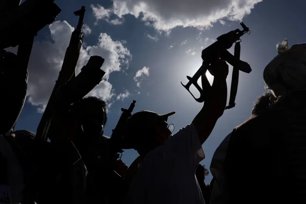 Silhouetted figures raising rifles against a bright sky with clouds.