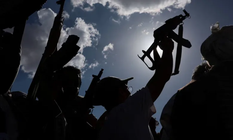 Silhouetted figures raising rifles against a bright sky with clouds.