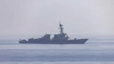 US Navy Arleigh Burke-class destroyer sailing on the ocean with a helicopter on the deck.