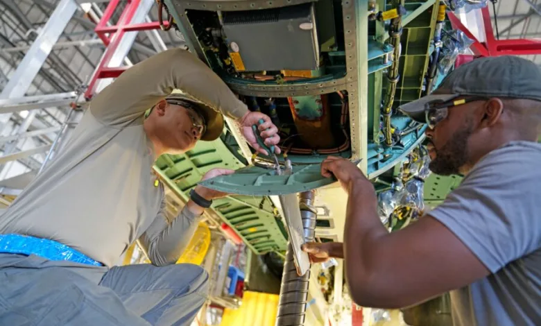 Airmen work on aircraft maintenance, inspecting and repairing components in a hangar.