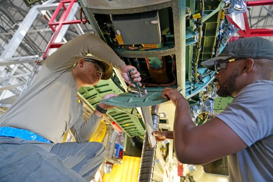 Airmen work on aircraft maintenance, inspecting and repairing components in a hangar.