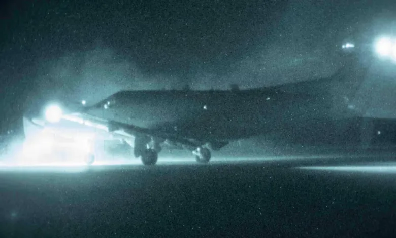 Airplane landing at night with bright landing lights illuminating the runway.